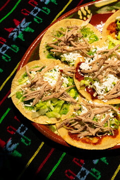 Traditional Mexican food known as chalupas prepared with green and red sauces with cheese, lettuce and onion. Mexican homemade food gastronomic icon
