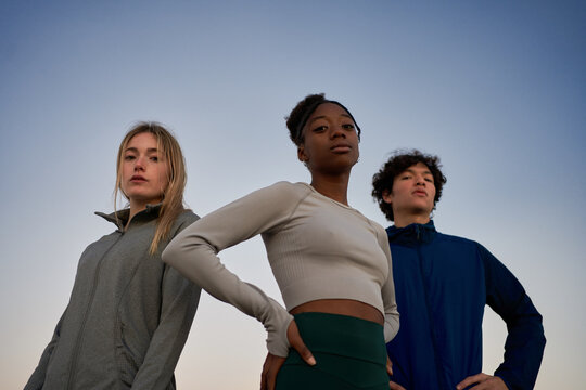 Diverse young sportspeople standing under blue sky