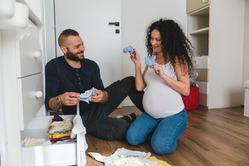 Playful Couple Preparing Clothes for the Baby Arrival
