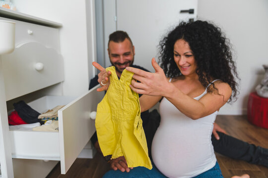 Pregnant Woman Looking at Baby Clothing at Home