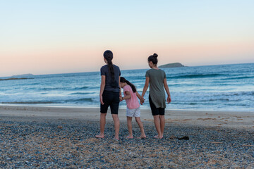 Young girls holding hand and walking together, embracing nature on the beach, sea landscape. 