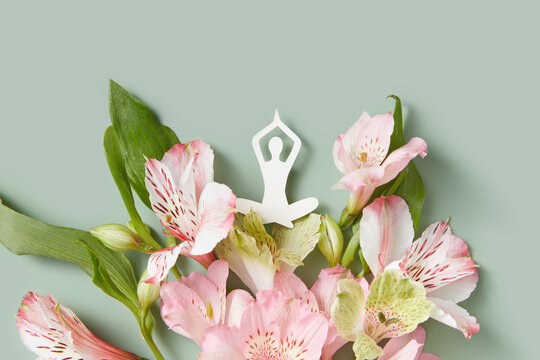Paper female figure meditating on bouquet of spring flowers