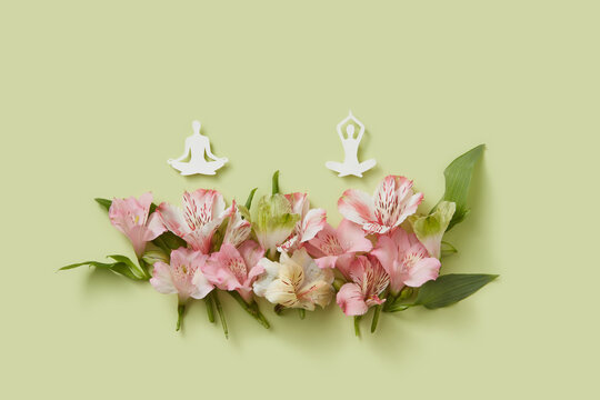 Two paper figures practicing yoga over spring flowers