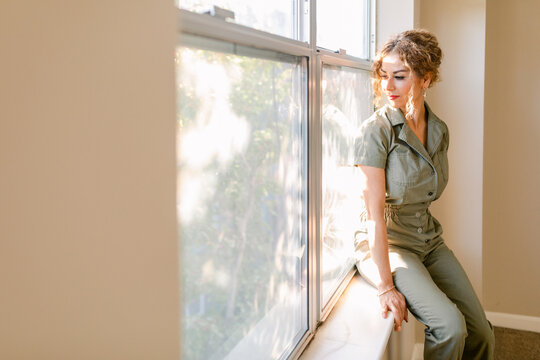 Elegant woman sitting looking out the window in duplex