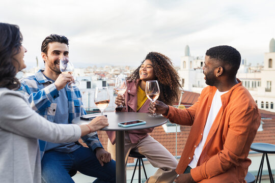 Black couple drinking wine and laughing on terrace
