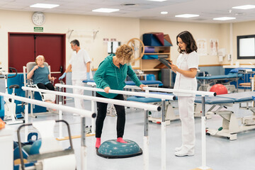 Female physiotherapist checking up mature patient