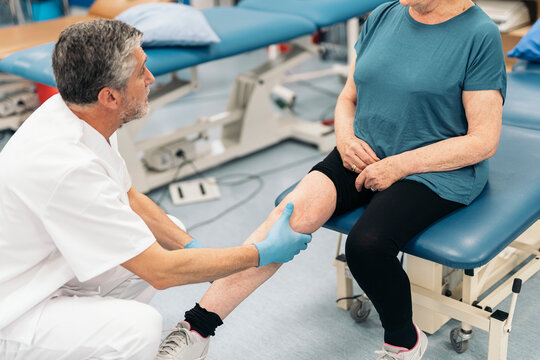 Male doctor examining motor system of senior woman