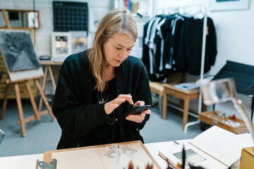 Artist browsing smartphone in art studio