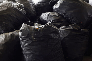 Big pile of old black trash bags filled with trash.