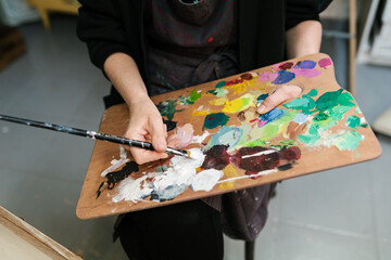 Crop painter with colorful palette in art studio