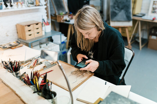 Painting artist photographing a sketch in the creative workshop