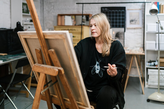 Focused woman drawing on easel in art studio