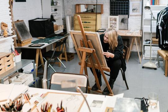 Craftswoman drawing on easel in art workshop