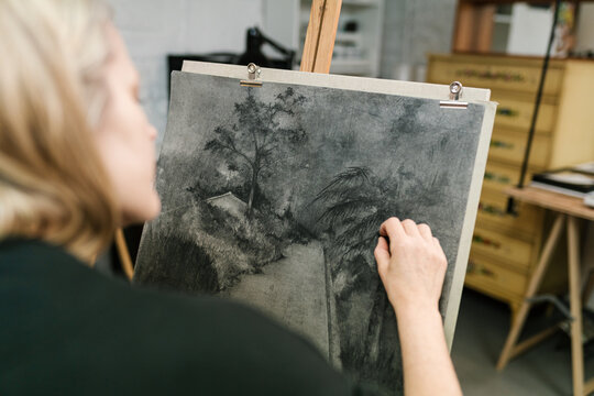 Craftswoman painting with charcoal on canvas