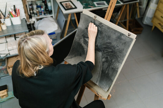 Artist painting with charcoal on wooden easel