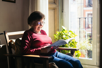 Elderly woman reading a book at home