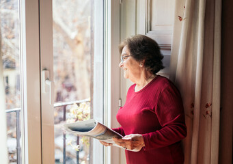 Old woman reading the newspaper at home