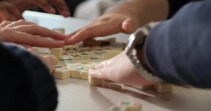 people playing Chinese mahjong game. Hands shuffling mahjong tiles. Slow motion