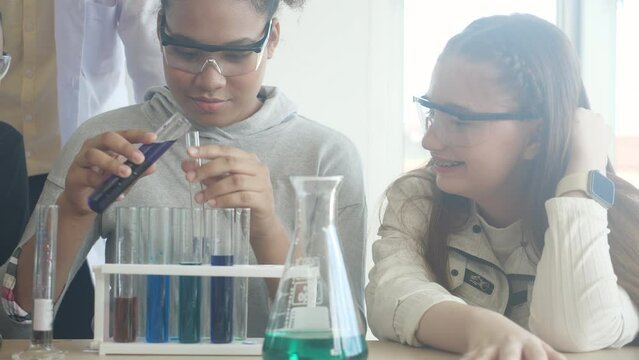 Young teacher teaching group student about science and explaining chemical for liquid in the lab of school, children studying and learning experiment science in the laboratory, education concept.