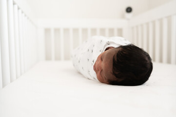 Baby laying in crib with camera watching