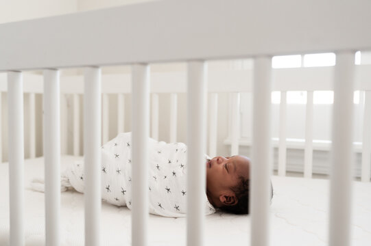 A baby laying in a simple crib