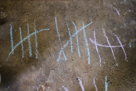 A Child's Chalk Written Tally Marks On Garage Floor