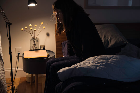 Tired sleepy woman sits on side of the bed
