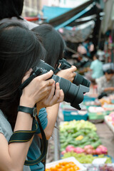 Two Thai female street photographers take photo at local market in Thailand.