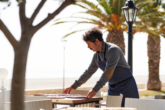 Male waiter adjusting placemats on table