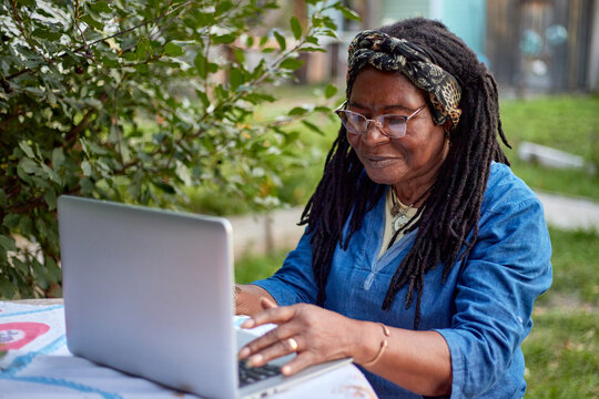 Elderly woman  with a laptop in the garden