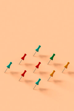 a row of colorful push pins on pink background