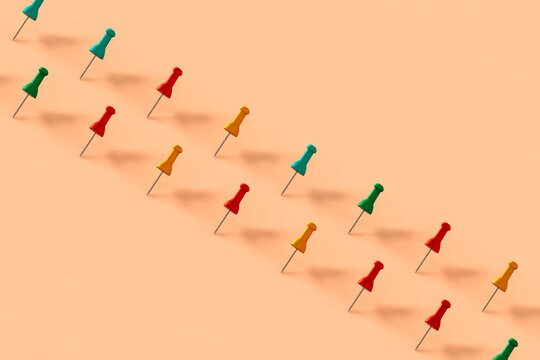 a row of colorful push pins on pink background
