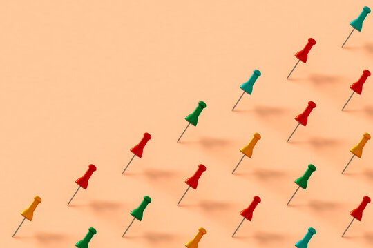 a row of colorful push pins on pink background