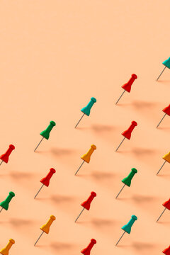a row of colorful push pins on pink background