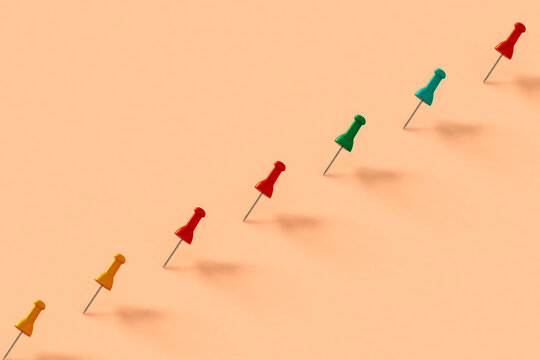 a row of colorful push pins on pink background
