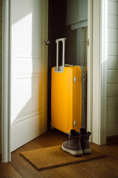Plastic Yellow Travel Suitcase Stands Near The Door 