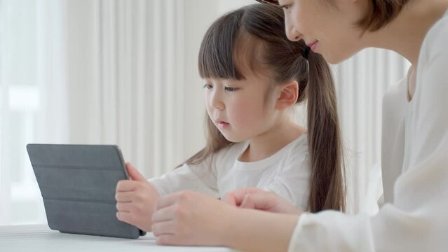 タブレットを使って学習する娘と母
