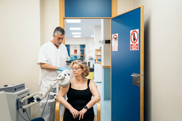 Doctor using rehabilitation apparatus on arm of woman