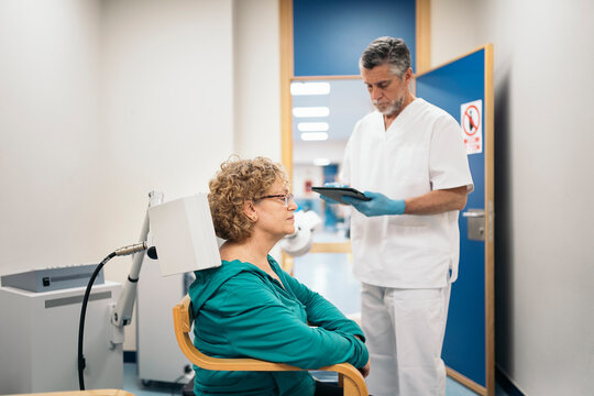 Doctor using rehabilitation apparatus on arm of woman