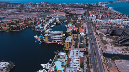 Fototapeta na wymiar aerial drone shots of the beach city of Lechería, with a residential area of Venice-style stilt houses, you can see houses, editions, canals, houses on the sea, stilt houses, parking lots, swimming po
