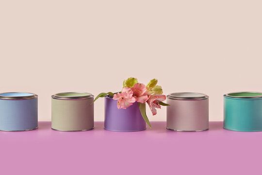 Row of colored tin cans for paint with spring flowers