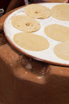Tortillas on a clay comal in a kitchen in Oaxaca