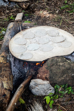 Tortillas on a comal that is on top of rocks 