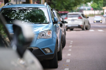 Fototapeta na wymiar Cars parked in line on city street side. Urban traffic concept