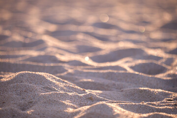 Close up of clean yellow sand surface covering seaside beach illuminated with evening light. Travel and vacations concept