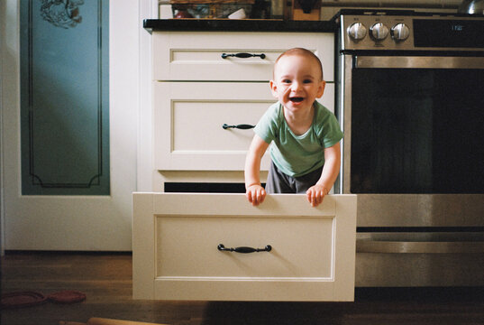 Cute Funny Baby Climbing into Kitchen Drawers