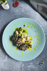 Fish cutlets in sesame seeds with broccoli and cauliflower. Keto menu for restaurant. Fishcake with vegetable mix on stone table. Healthy fish dish for diet. Salmon cutlet in blue plate.