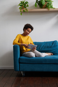 Woman smiling while holding a tablet computer in a living room