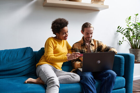 Diverse couple with credit card shopping online on laptop