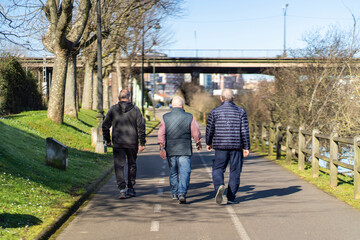 Anonymous pensioners walking on asphalt path